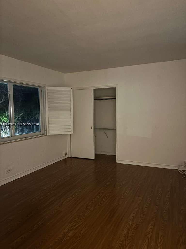Wood-finish flooring, white plantation shutters, and a reach-in closet with sliding doors
