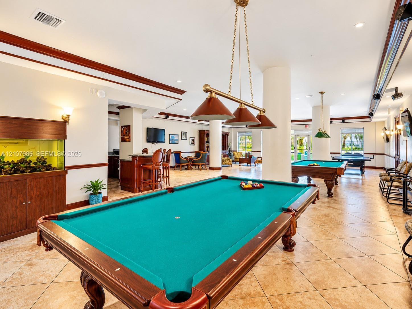Recreation space featuring ceramic tile flooring, crown molding, built-in cabinetry, recessed lighting, and metal pendant lighting fixtures