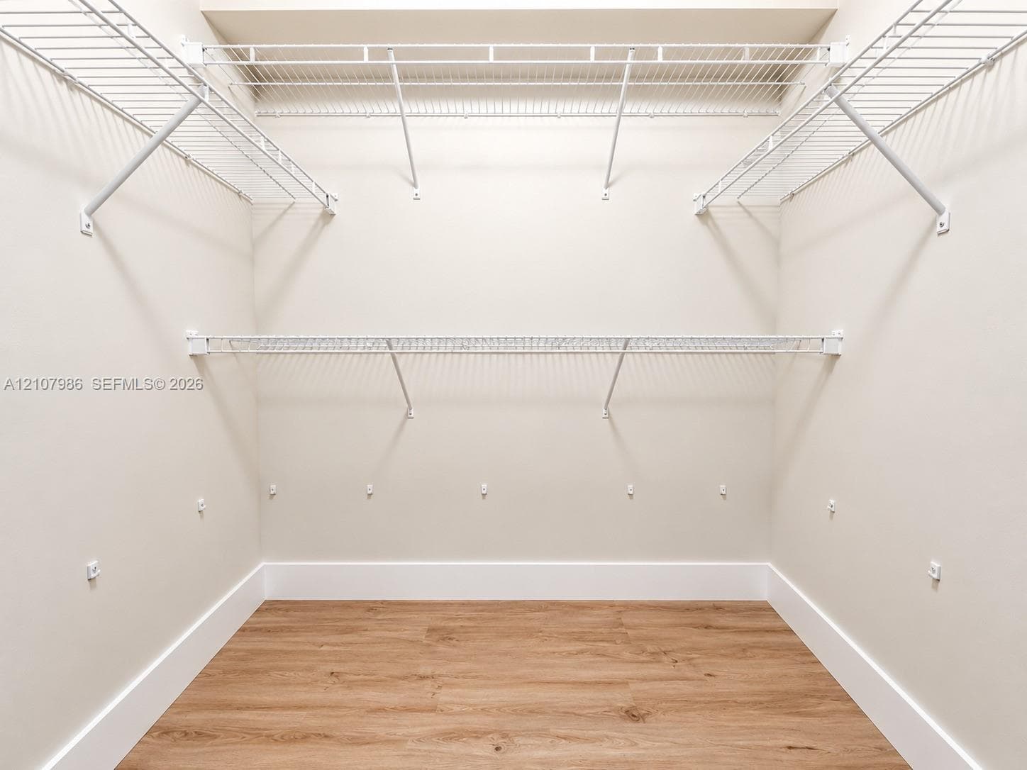 Storage area featuring wood-finish flooring and tiered white wire shelving
