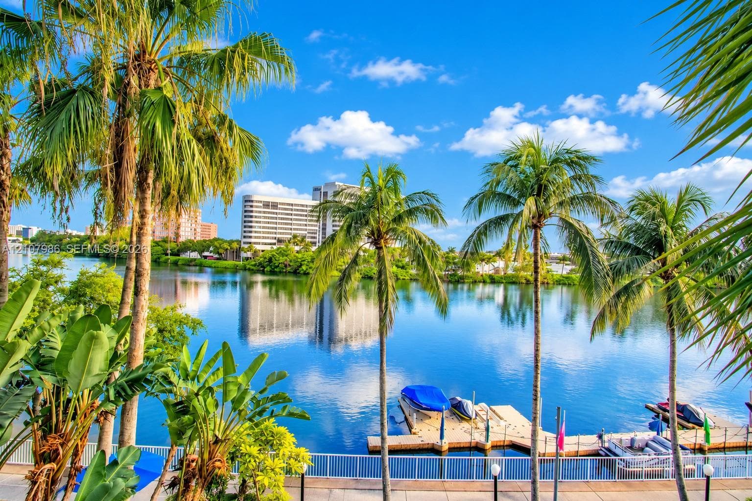 Waterfront property featuring a private boat dock, concrete bulkhead, and mature palm trees
