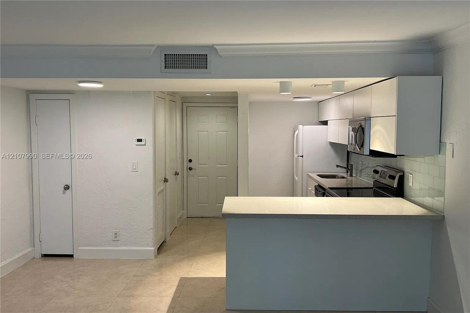 Kitchen featuring flat-panel cabinetry, a stone-surface breakfast bar, subway tile backsplash, and tile flooring