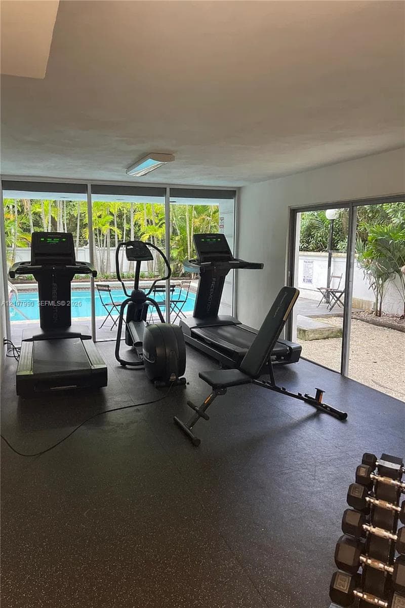 Fitness space featuring impact-resistant rubber flooring, floor-to-ceiling glass walls, and direct access to an outdoor swimming pool