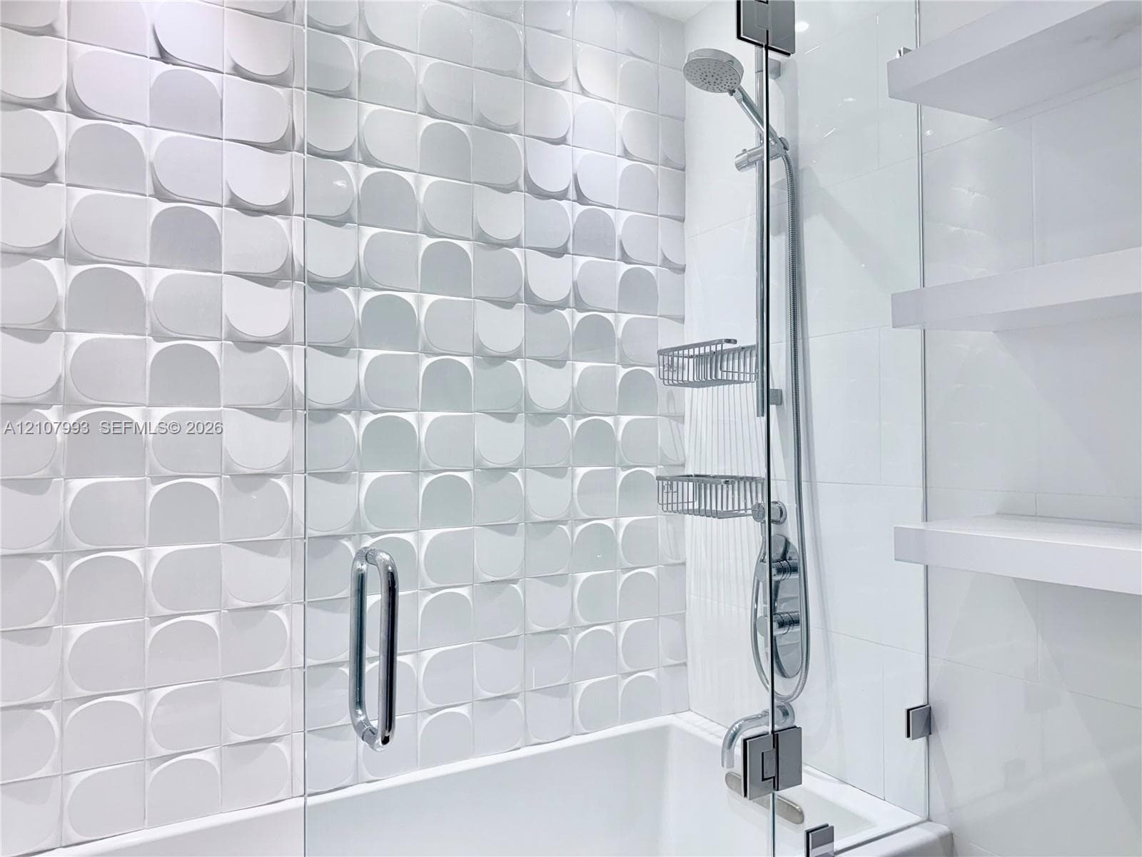 Textured three-dimensional wall tile, glass-enclosed shower, adjustable height handheld shower head, and built-in floating shelves