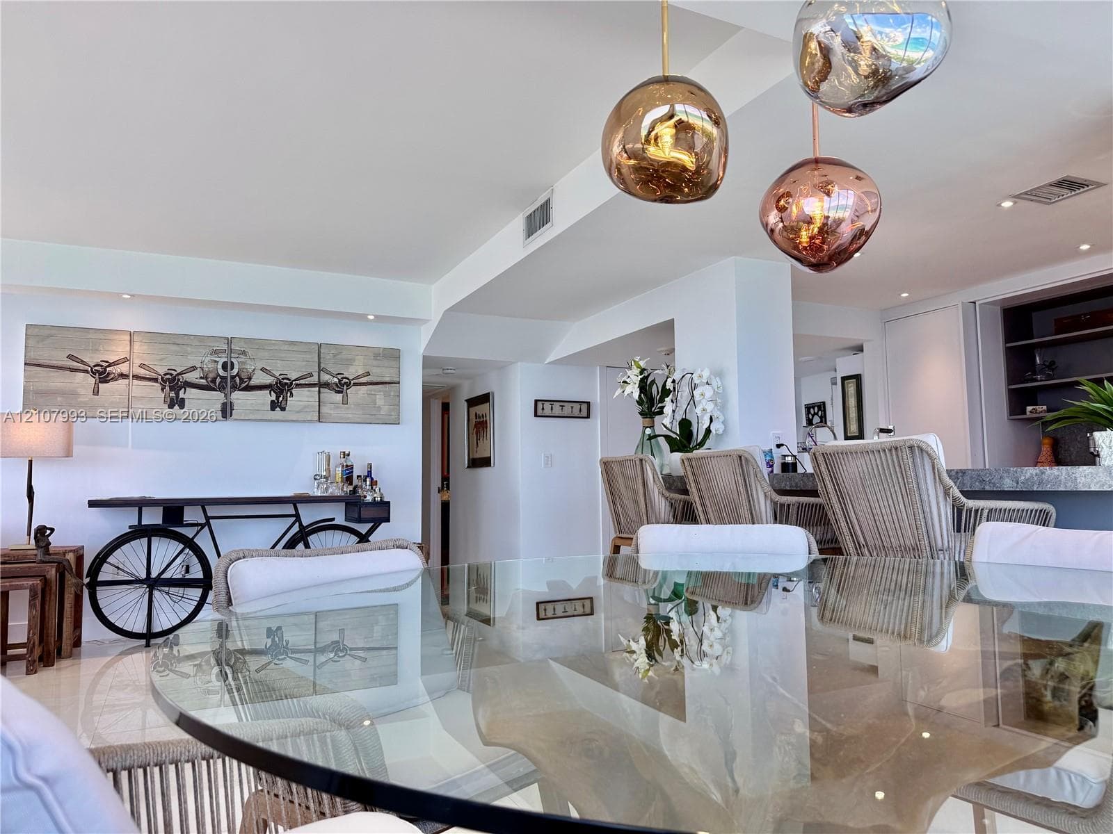 Open-concept space featuring metallic pendant light fixtures, polished stone flooring, and built-in shelving