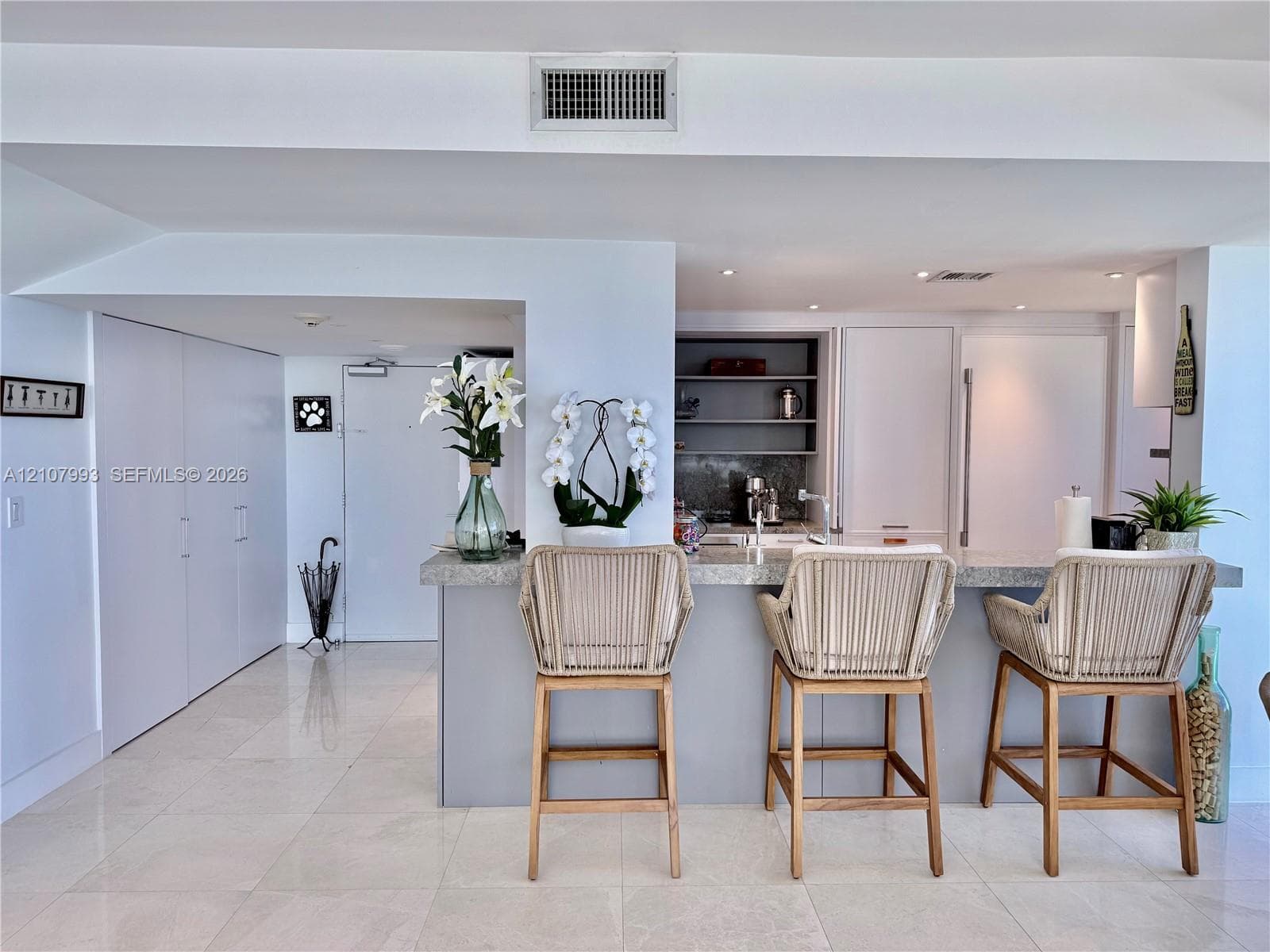Kitchen featuring a stone-topped breakfast bar, recessed ceiling lighting, built-in cabinetry, and tile flooring