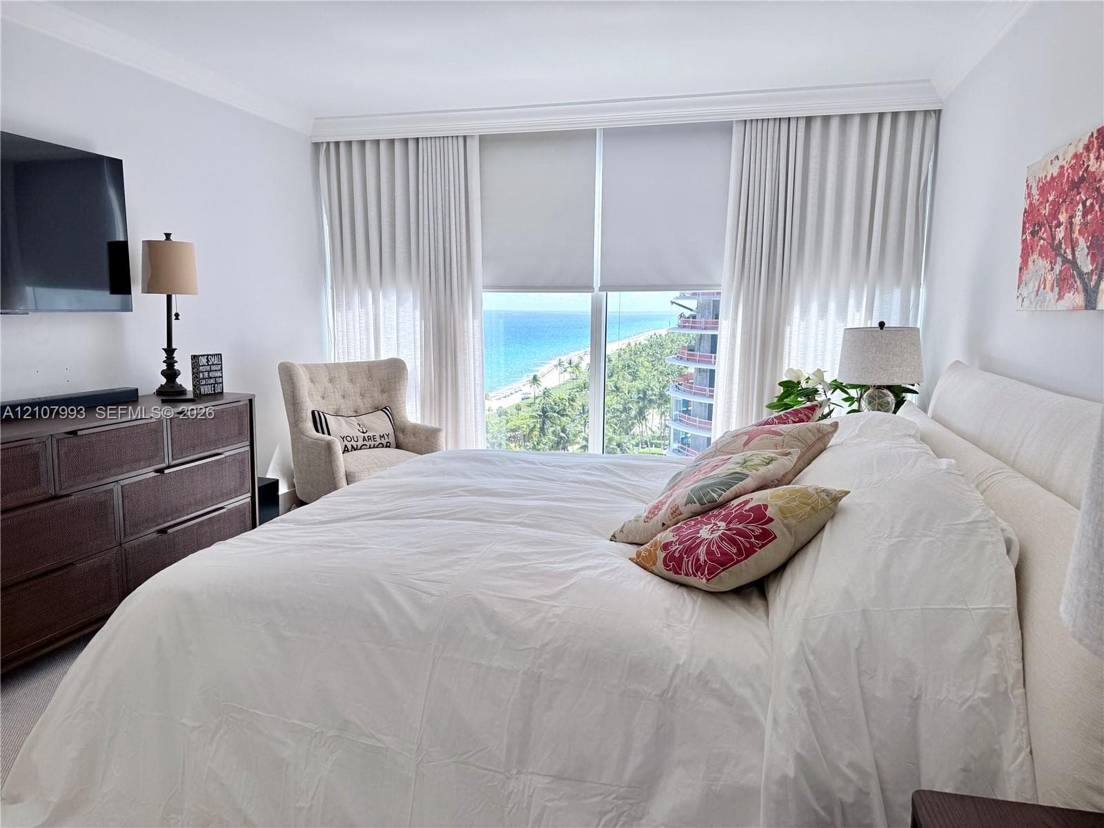 Floor-to-ceiling windows featuring coastal scenery, crown molding, and neutral wall-to-wall carpeting