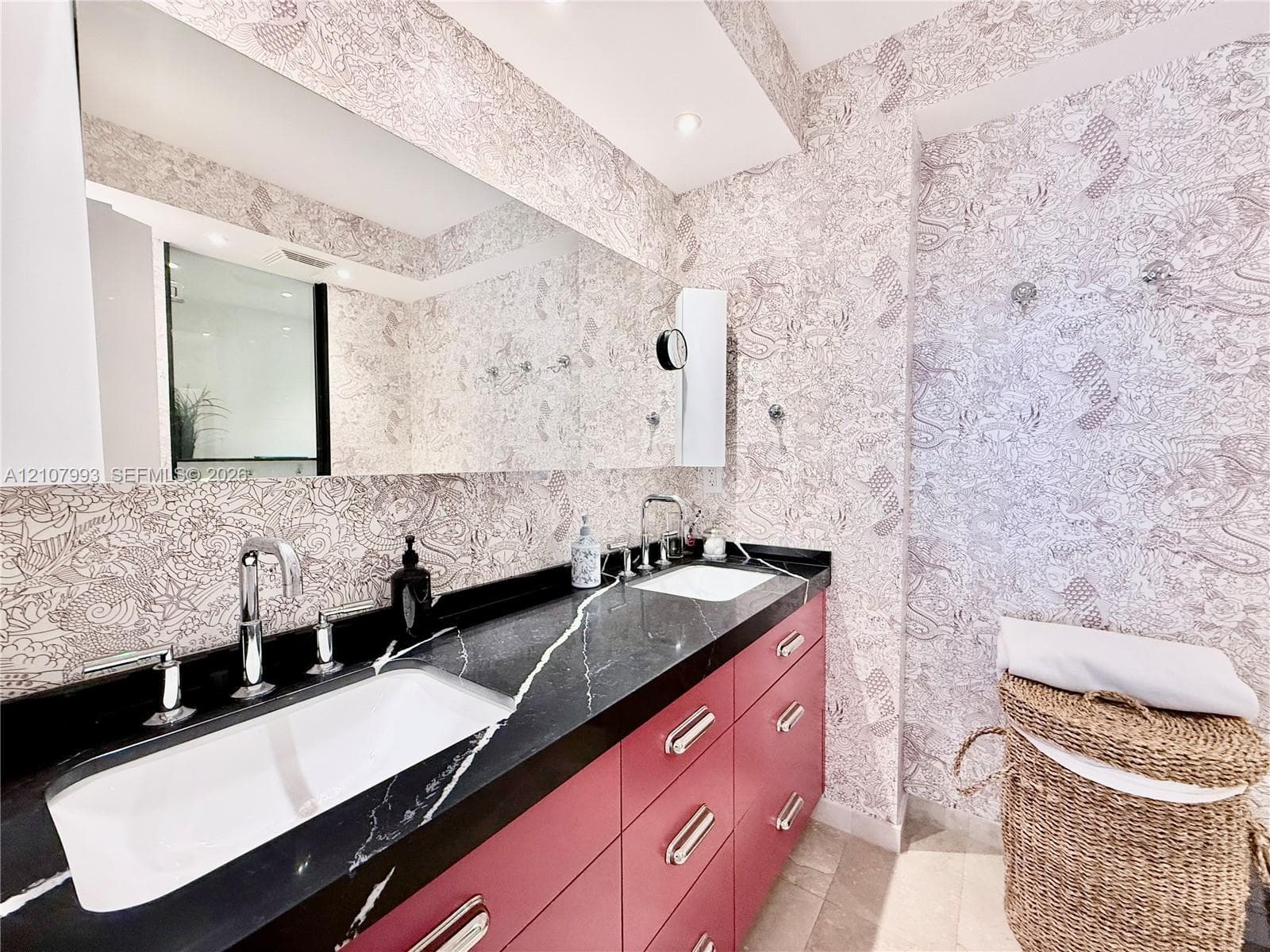 Custom vanity with matte-finish cabinetry, dark stone countertop with white veining, dual under-mount sinks, chrome widespread faucets, and wall-to-wall mirror