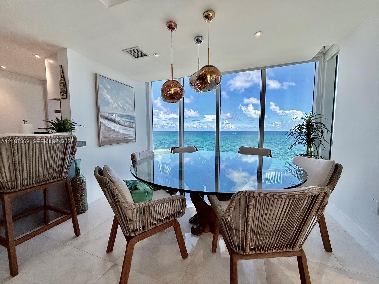 Floor-to-ceiling windows featuring ocean scenery, large-format tile flooring, and metallic spherical pendant lighting