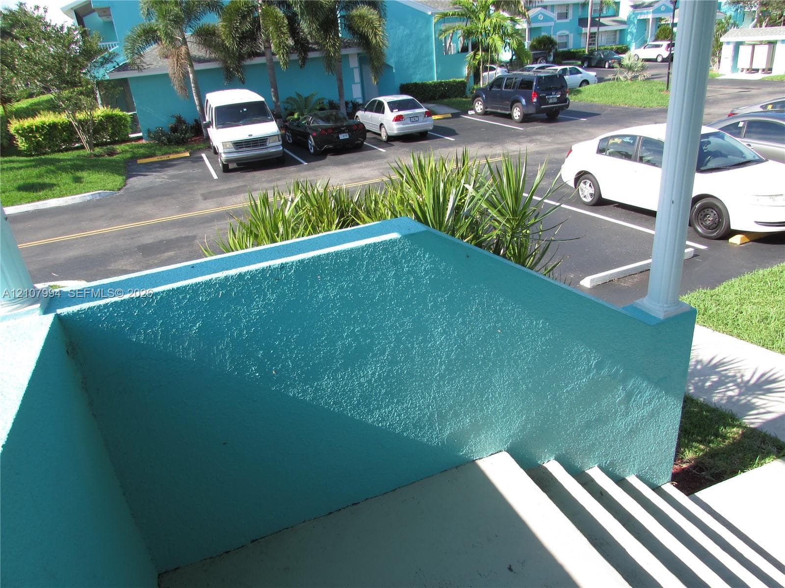Exterior landing featuring a textured stucco half-wall, painted finish, and a structural support column