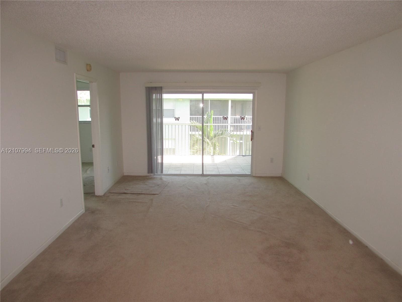 Neutral-toned carpeting and sliding glass doors providing outdoor access