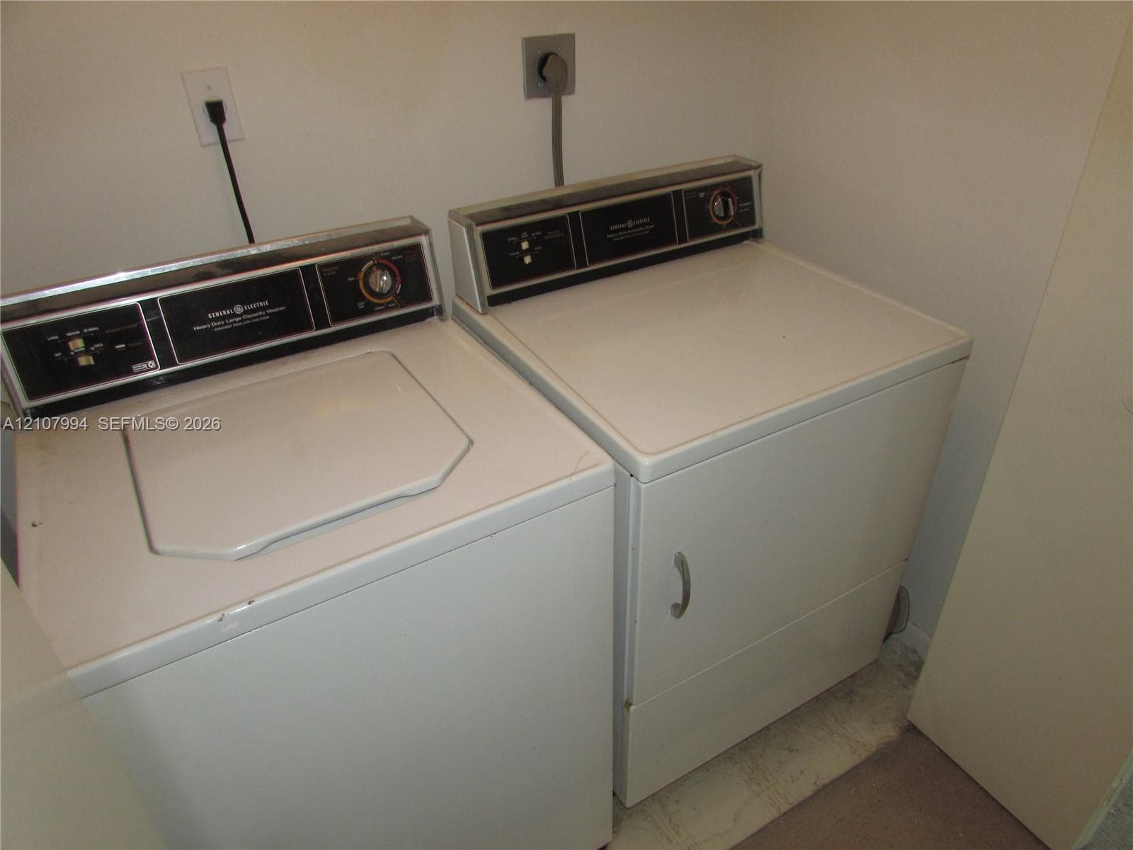 Laundry area featuring white top-load washer and matching front-load dryer with integrated control panels