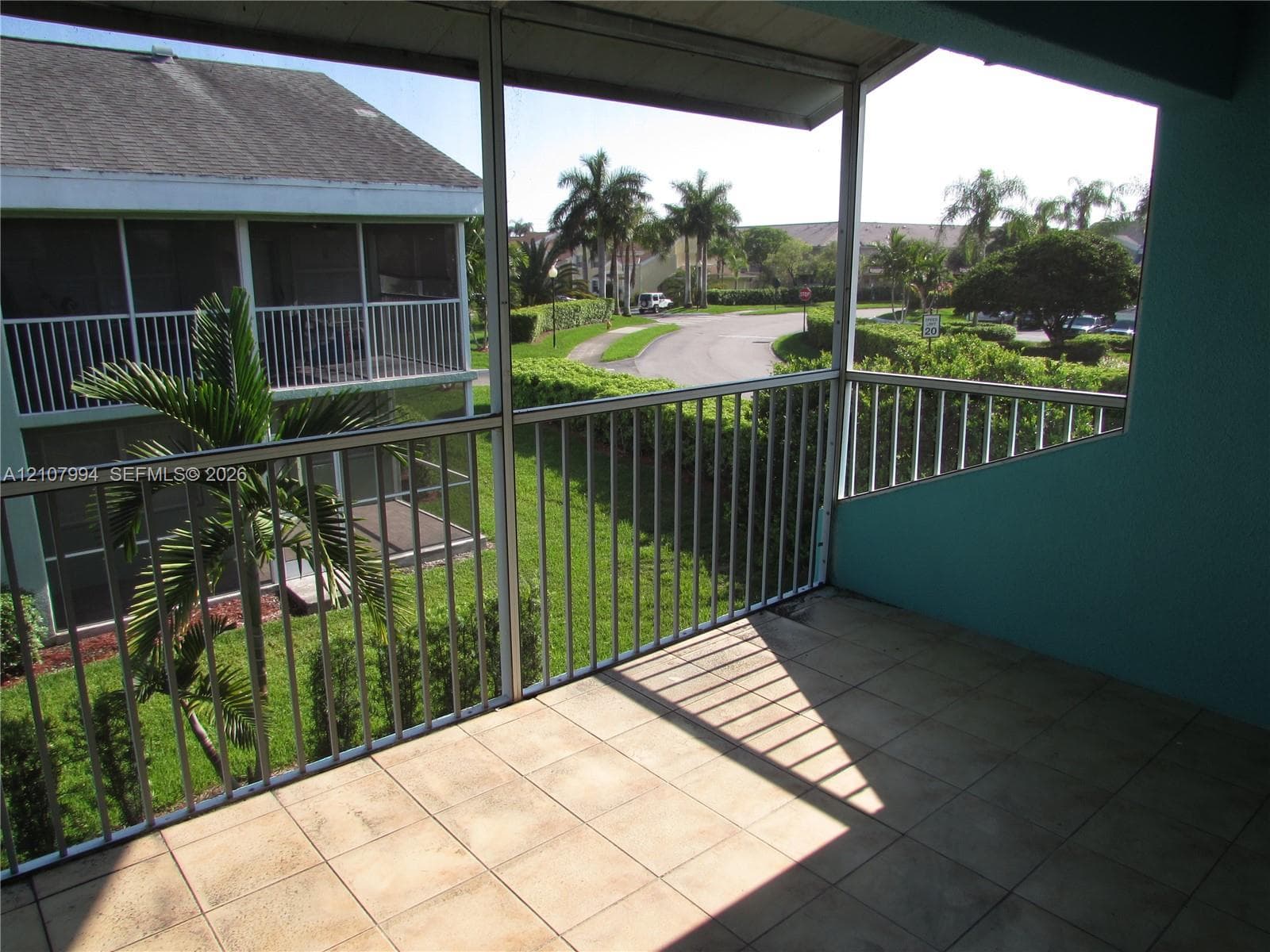 Screened-in balcony featuring square ceramic tile flooring, metal frame screening, and vertical metal railings