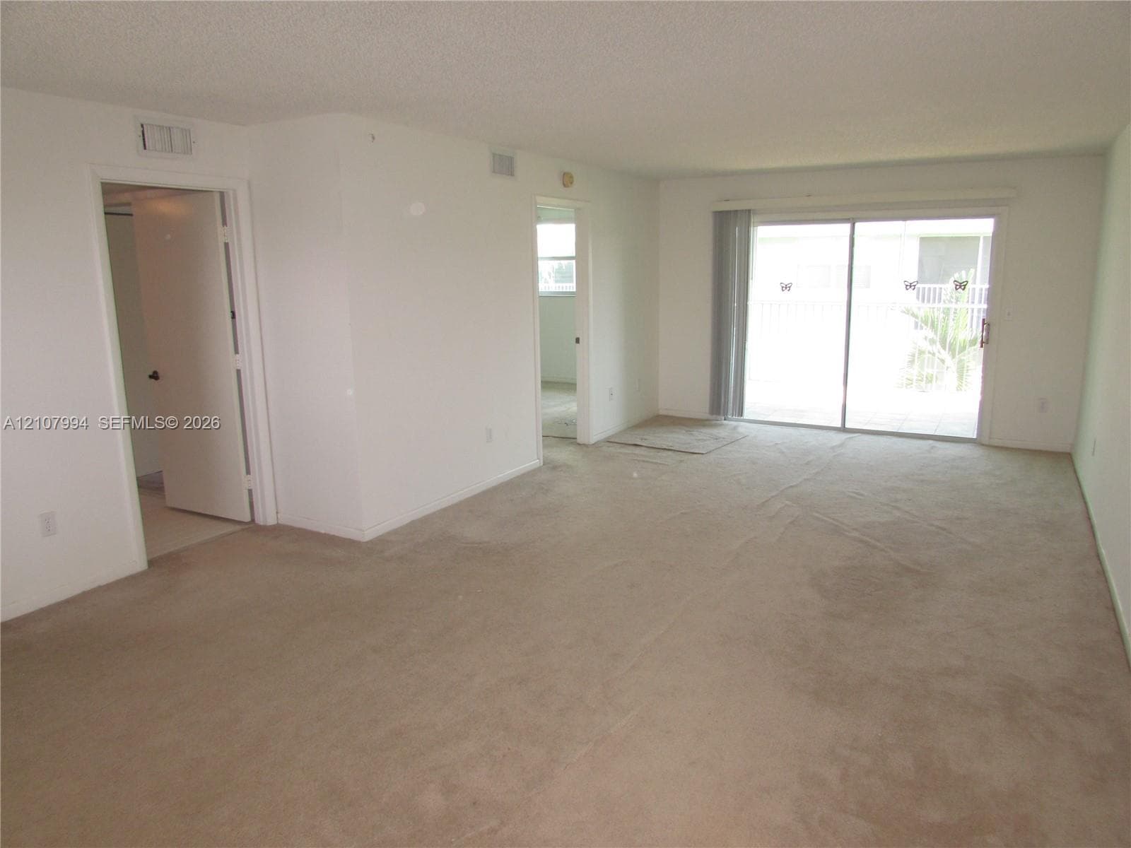 Living area featuring neutral carpeting and sliding glass doors with exterior access