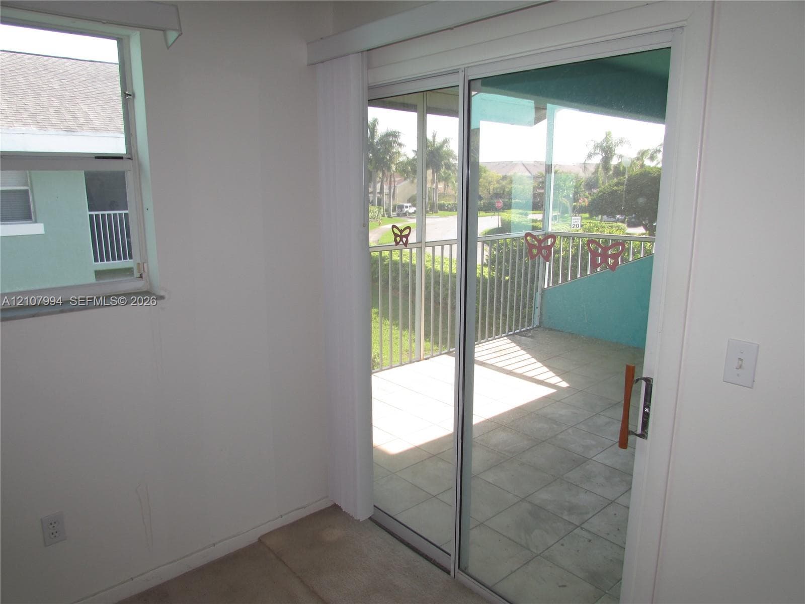 Sliding glass patio door, single-hung window, and private balcony featuring metal railing and tile flooring