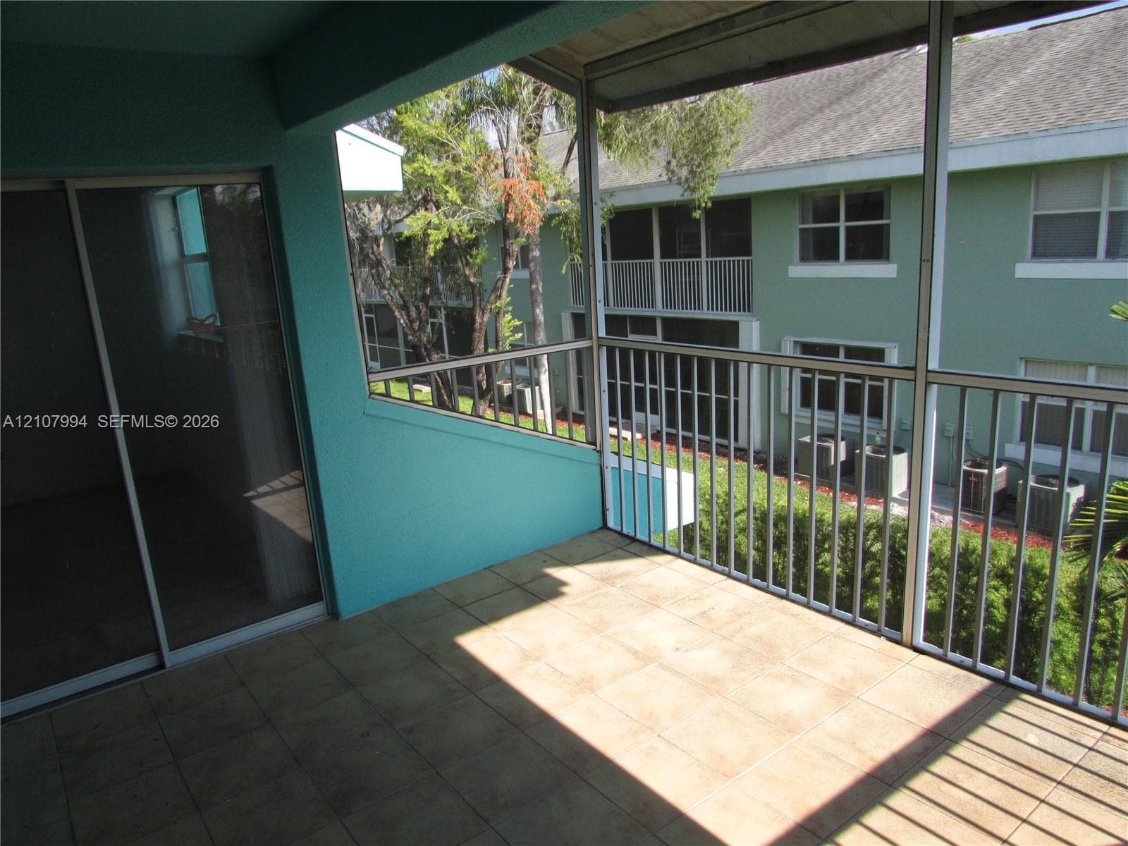 Screened-in balcony featuring tile flooring, metal railings, and a sliding glass door entry