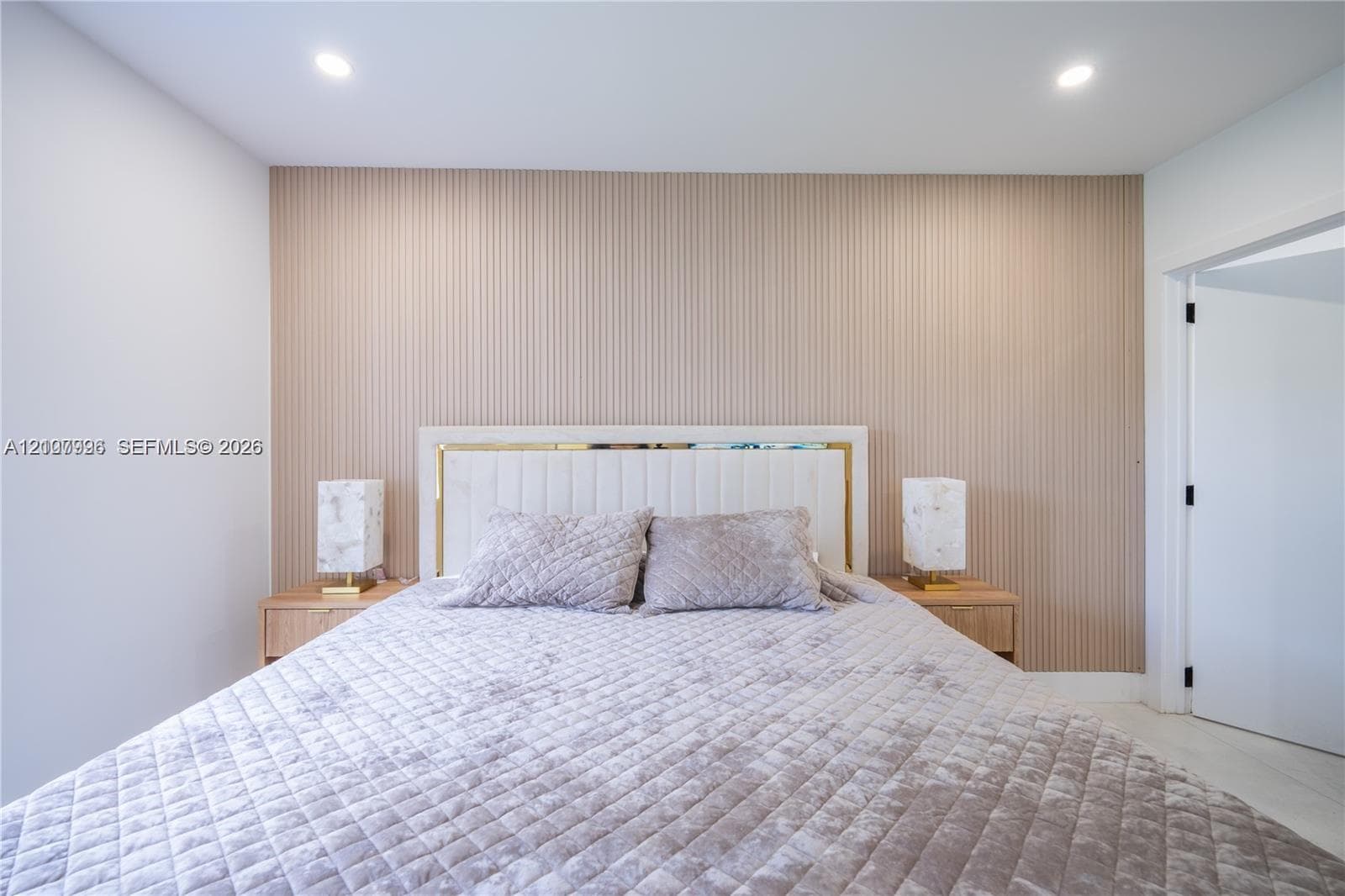 Textured vertical-slat accent wall, custom built-in headboard with integrated trim, and recessed ceiling lighting
