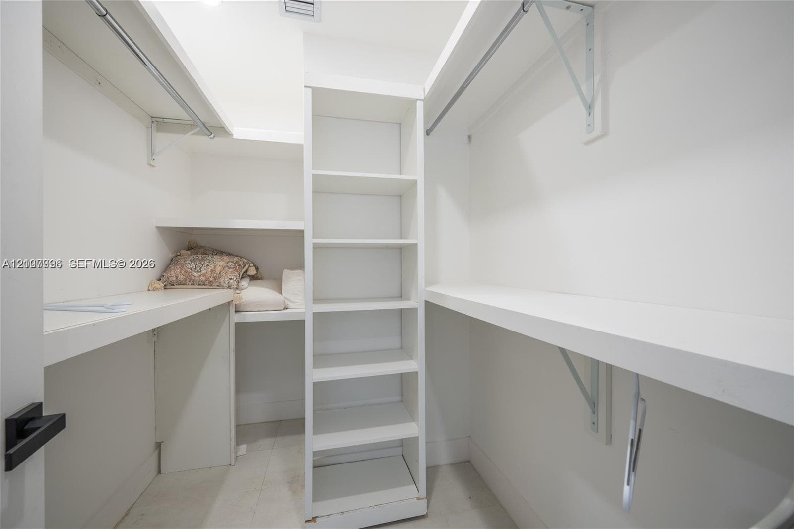 Walk-in closet featuring white built-in shelving, integrated hanging rods, and solid-surface shelving units