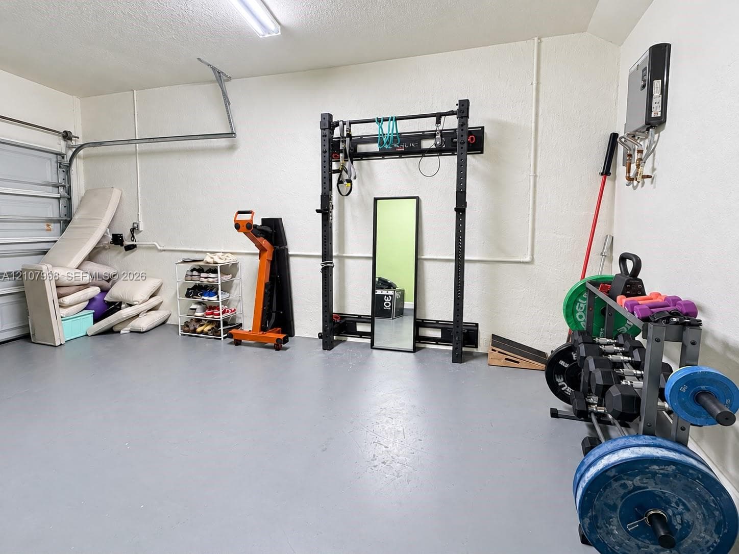 Multi-purpose garage space featuring painted concrete flooring, wall-mounted steel structure, and overhead LED lighting
