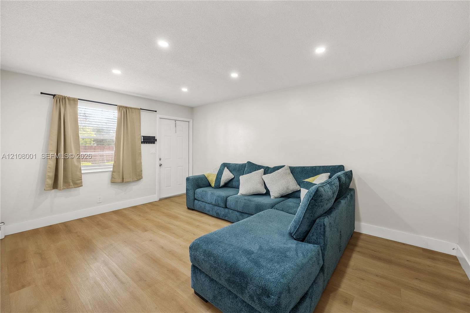 Interior space featuring wood-finish flooring, recessed lighting, and a single-panel door with hardware