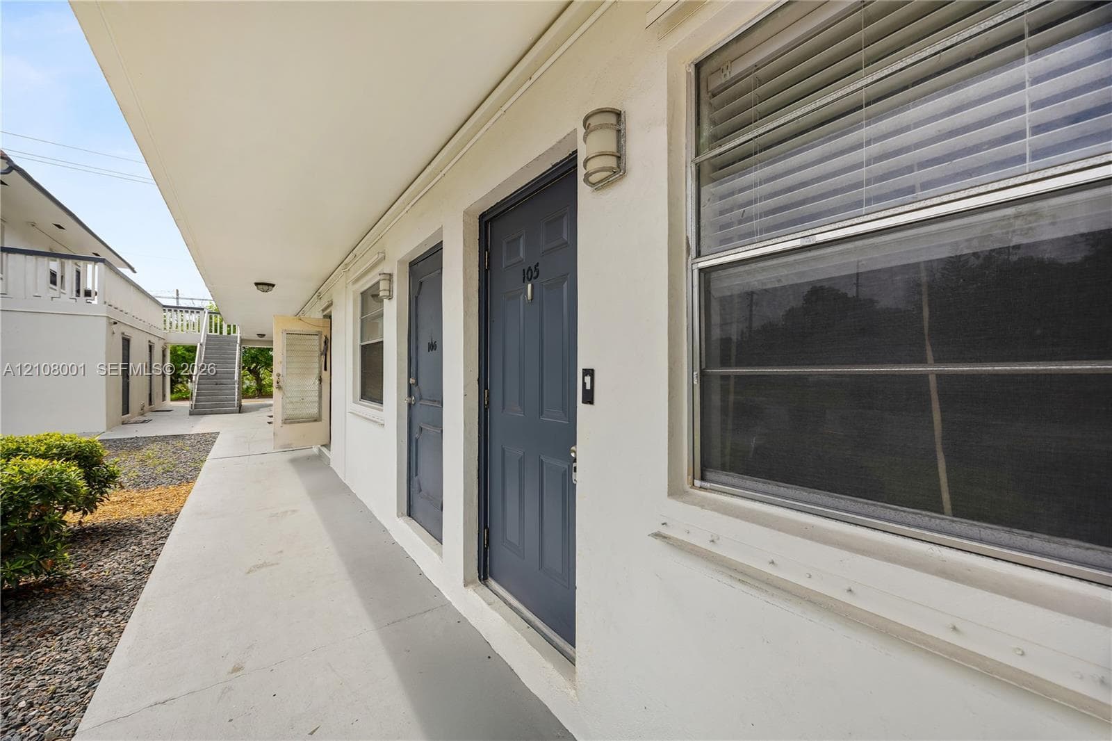 Covered concrete walkway featuring recessed lighting, smooth exterior stucco finish, and paneled entry doors