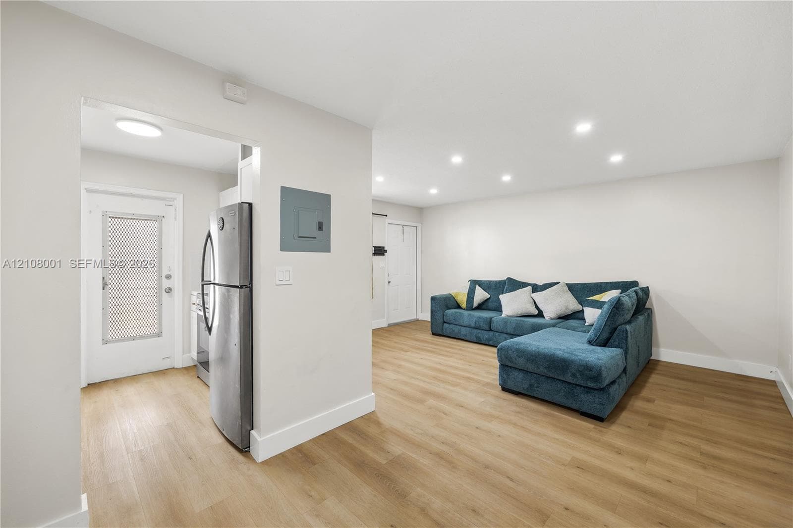 Open-concept interior featuring light wood-finish flooring, recessed lighting, and stainless steel kitchen appliances