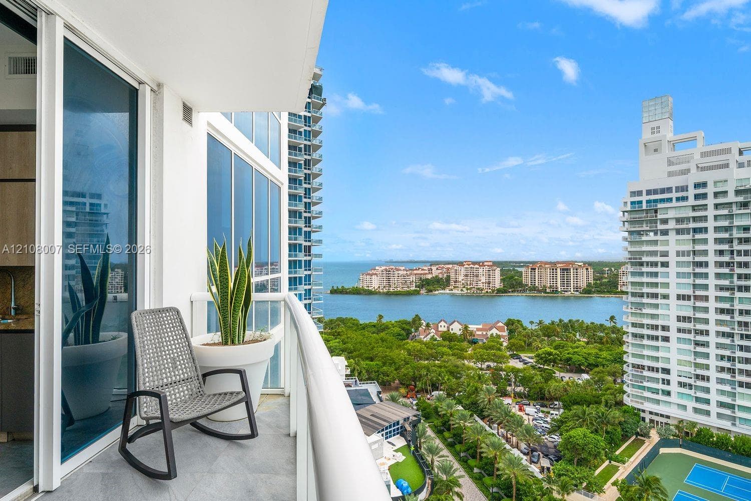 Private balcony with glass railing, stone-finish flooring, and floor-to-ceiling sliding glass doors