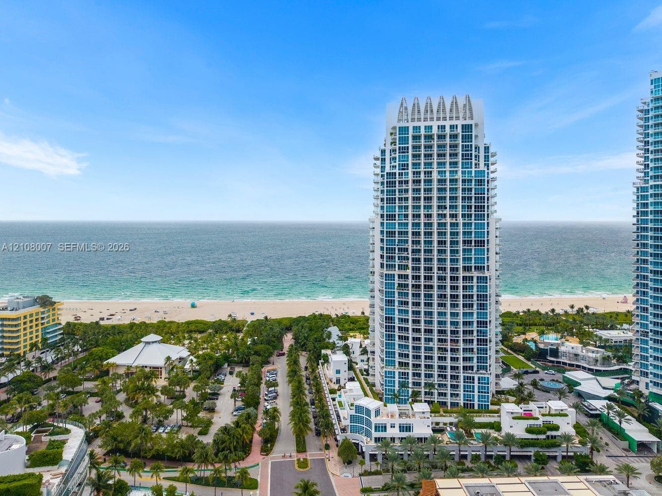 High-rise tower featuring glass-paneled balconies and a reinforced concrete structure, situated in proximity to the coastline
