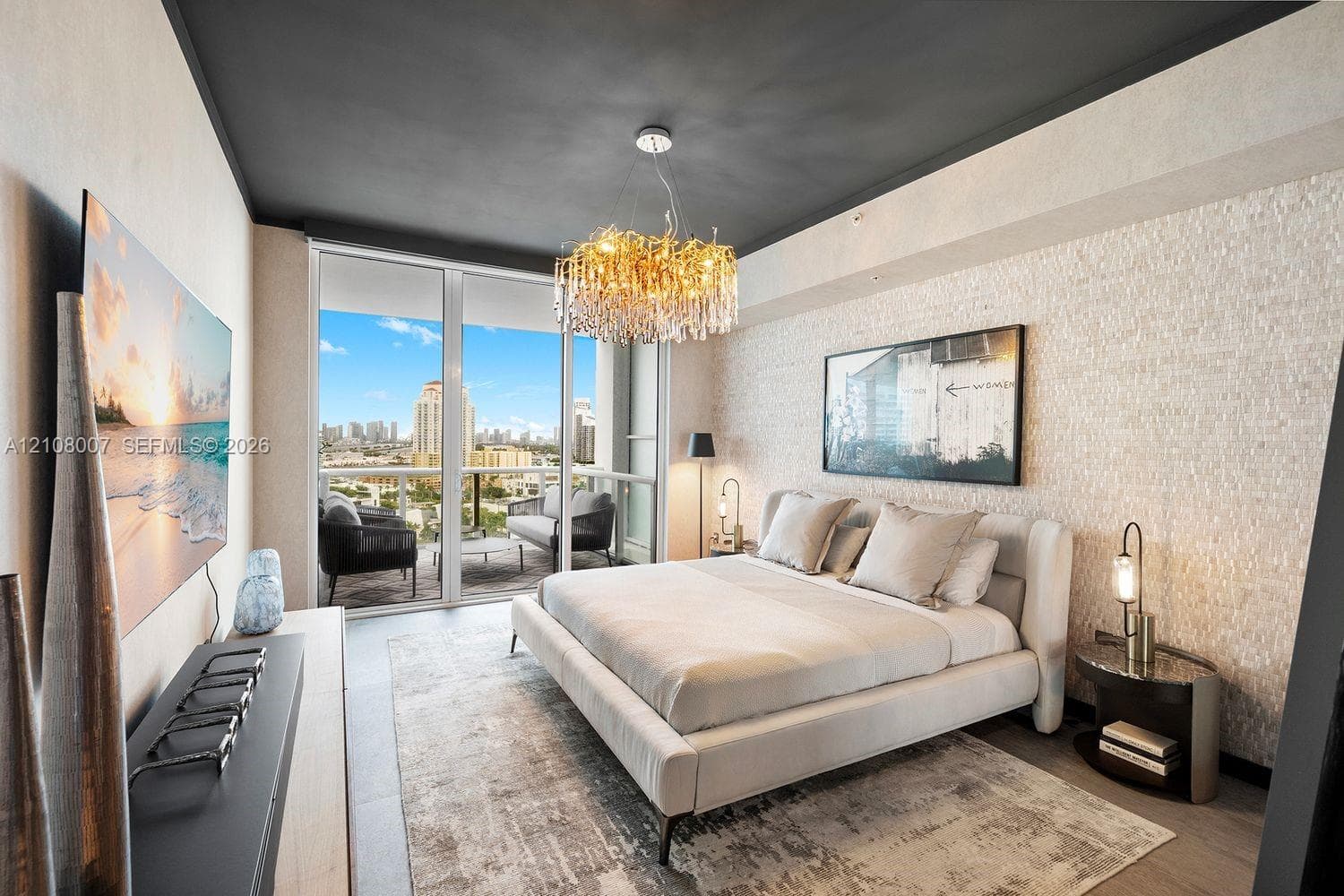 Textured stone accent wall, floor-to-ceiling glass paneling, private balcony, and decorative crystal chandelier