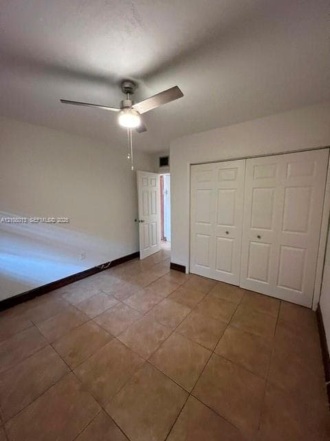 Tile flooring, dual six-panel sliding closet doors, and a ceiling fan with integrated light fixture