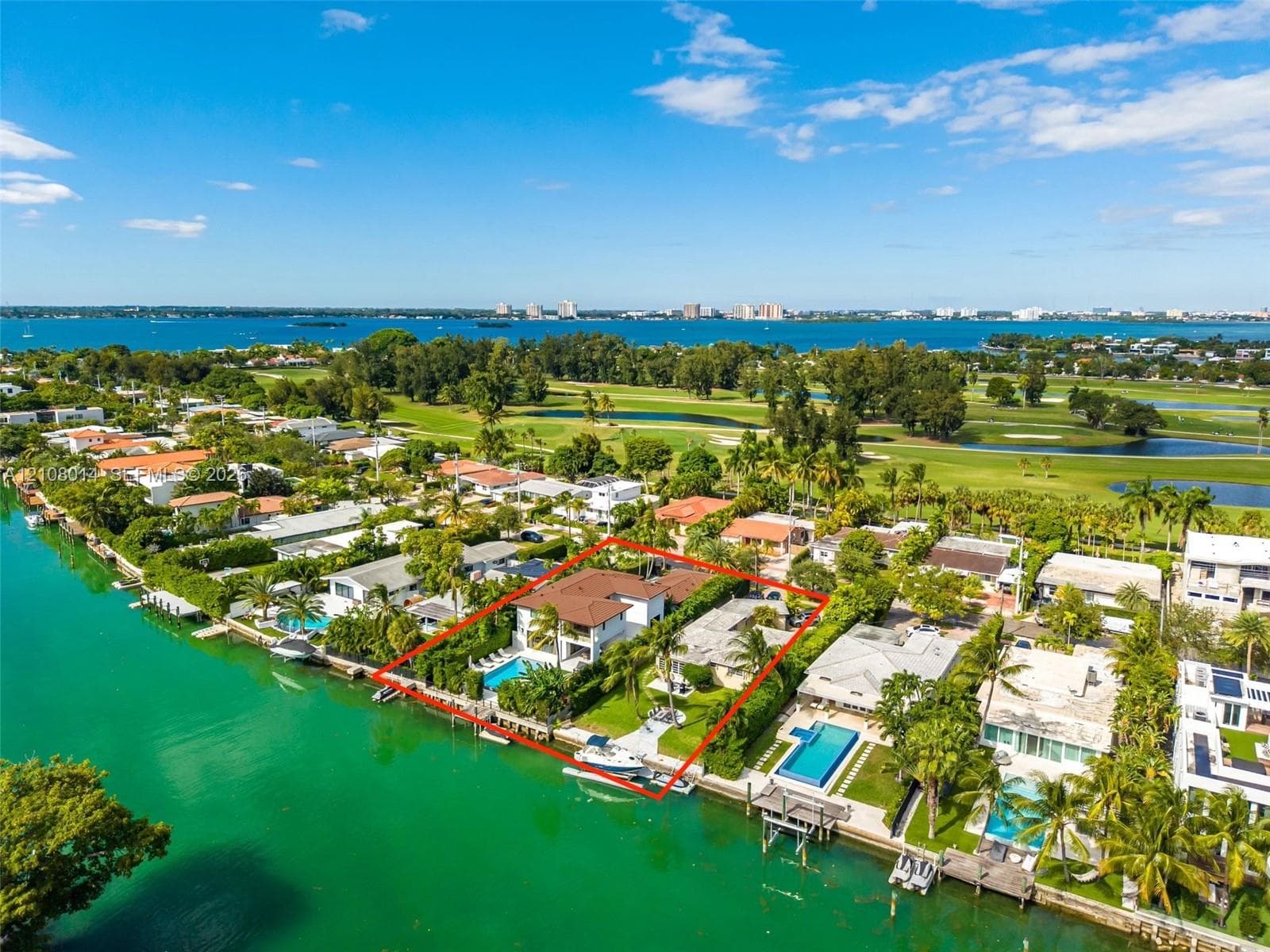 Waterfront property featuring a private swimming pool, concrete bulkhead, boat dock, and expansive lawn area