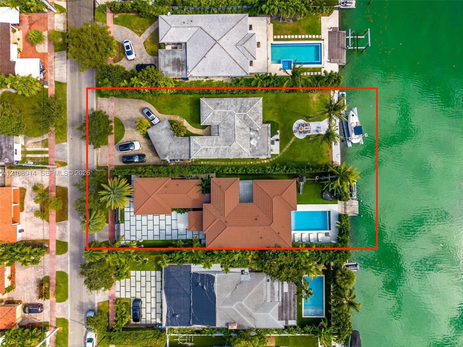 Waterfront property featuring a private boat dock, swimming pool, large paved patio, and multi-car driveway