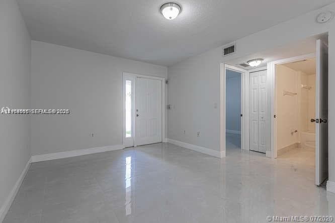 Neutral-toned interior featuring glossy tile flooring, recessed and flush-mount lighting, a six-panel exterior door with sidelight, and a walk-in closet with six-panel double doors