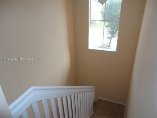 Staircase featuring a white wooden balustrade and a large window with a muntin grid