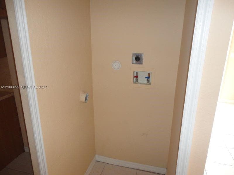Utility alcove featuring a recessed water supply box, integrated electrical outlet, and an exhaust vent