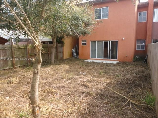 Rear exterior featuring stucco siding, sliding glass doors, and a wood privacy fence