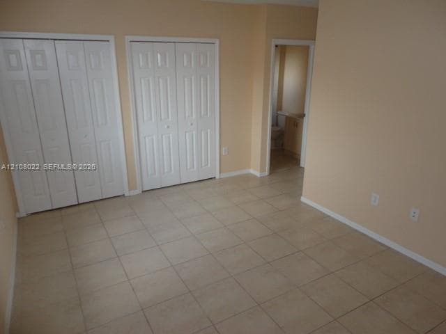 Ceramic tile flooring, two sets of white paneled bifold closet doors, and neutral wall paint