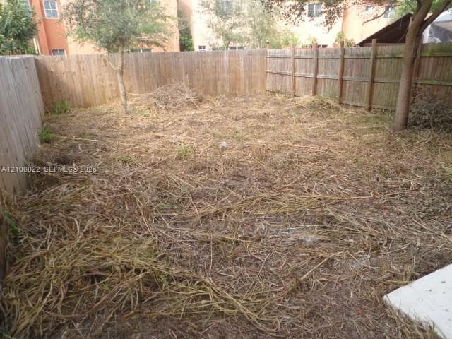 Enclosed backyard space featuring wood panel fencing and mature trees