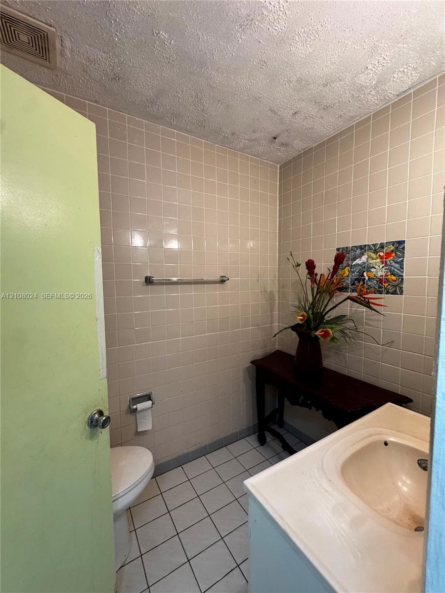Ceramic tile wall finishes, integrated vanity with recessed basin, and metal hardware fixtures