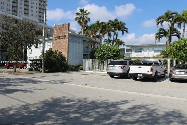 Exterior facade featuring stone veneer detailing, metal paneling, surface parking, and mature palm landscaping