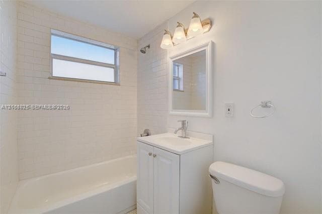 Bathroom featuring white subway tile wall surround, integrated vanity cabinet with a stone countertop, framed mirror, three-light vanity fixture, and a wall-mounted towel ring