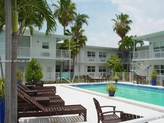 Swimming pool with tile surround, white metal railings, and mature palm trees