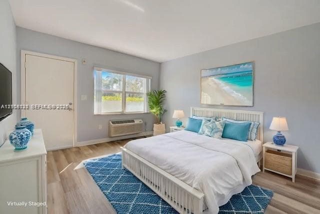 Bedroom featuring wood-finish flooring, a horizontal sliding window, and a wall-mounted climate control unit