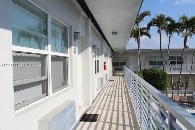 Exterior walkway featuring metal railings, sliding windows, and a covered balcony