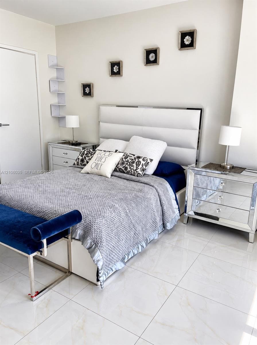 Large-format polished tile flooring featuring subtle neutral veining and wall-mounted white corner shelving