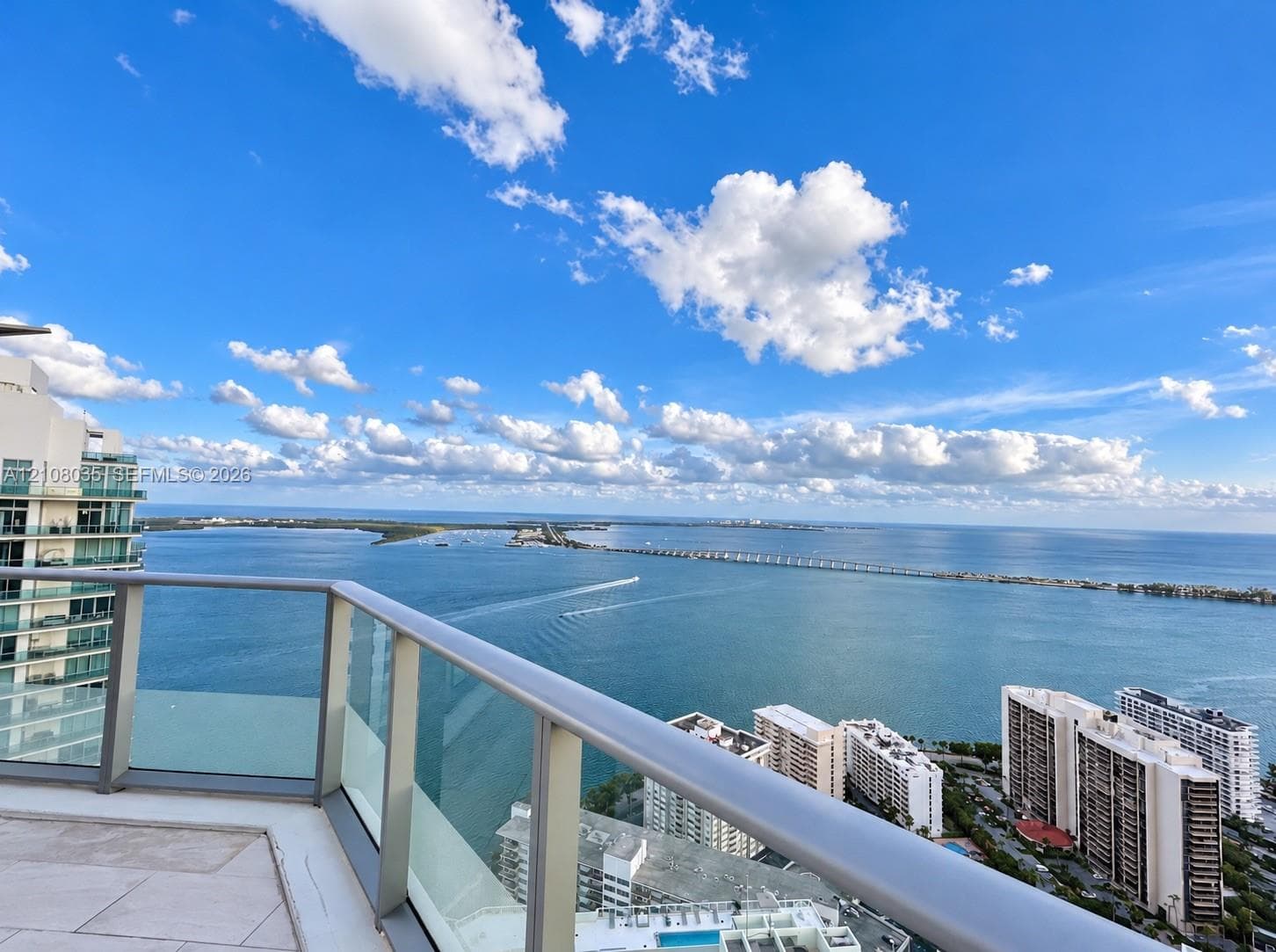 Private balcony featuring tile flooring and a glass-paneled railing overlooking the bay