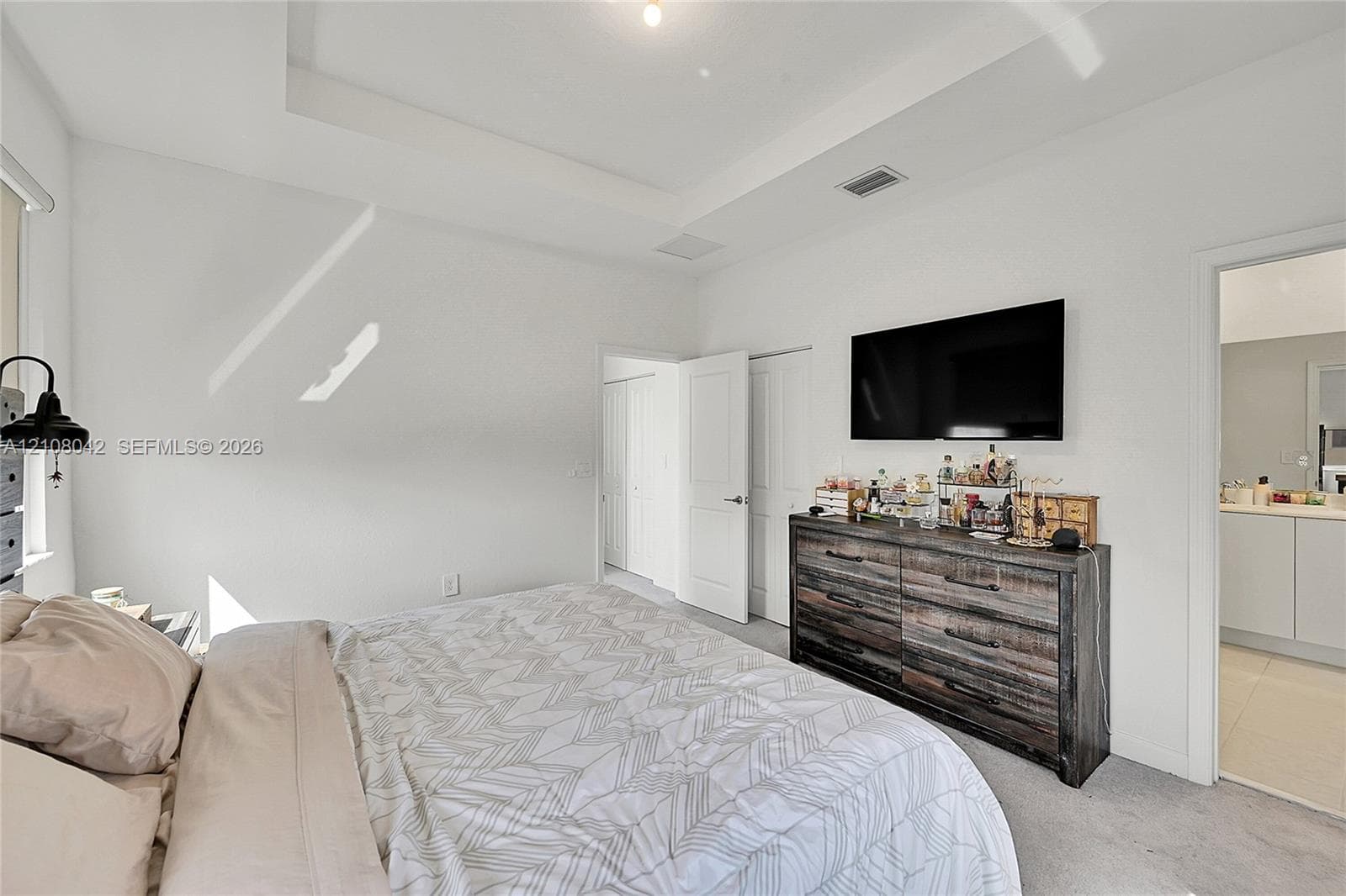 Tray ceiling featuring recessed lighting and neutral wall finishes, complemented by interior panel doors