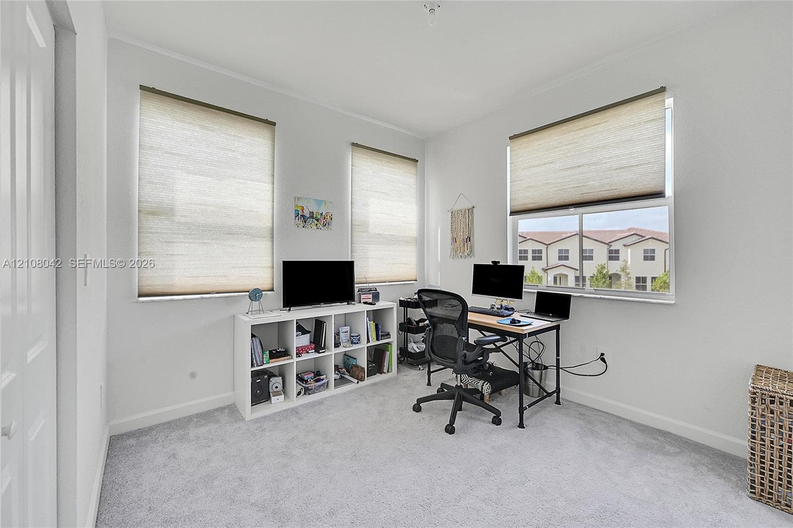 Neutral interior room featuring wall-to-wall carpeting, three multi-pane windows, and neutral roller shades