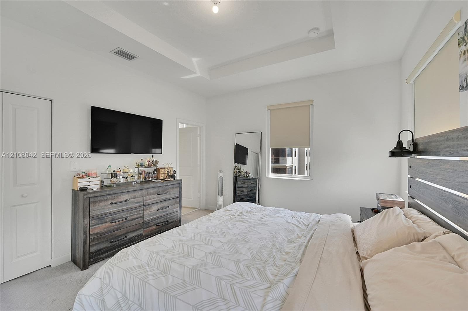 Tray ceiling, neutral wall finishes, and integrated wall-mounted lighting fixture