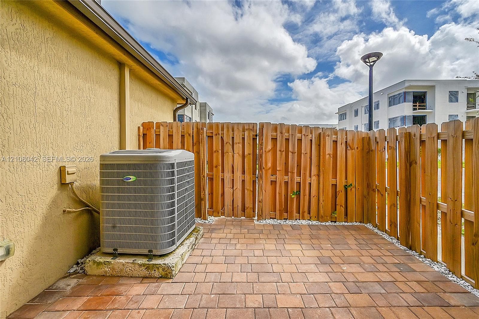 Private backyard retreat featuring a brick-paver patio, horizontal wood-finish privacy fencing, and a central HVAC unit
