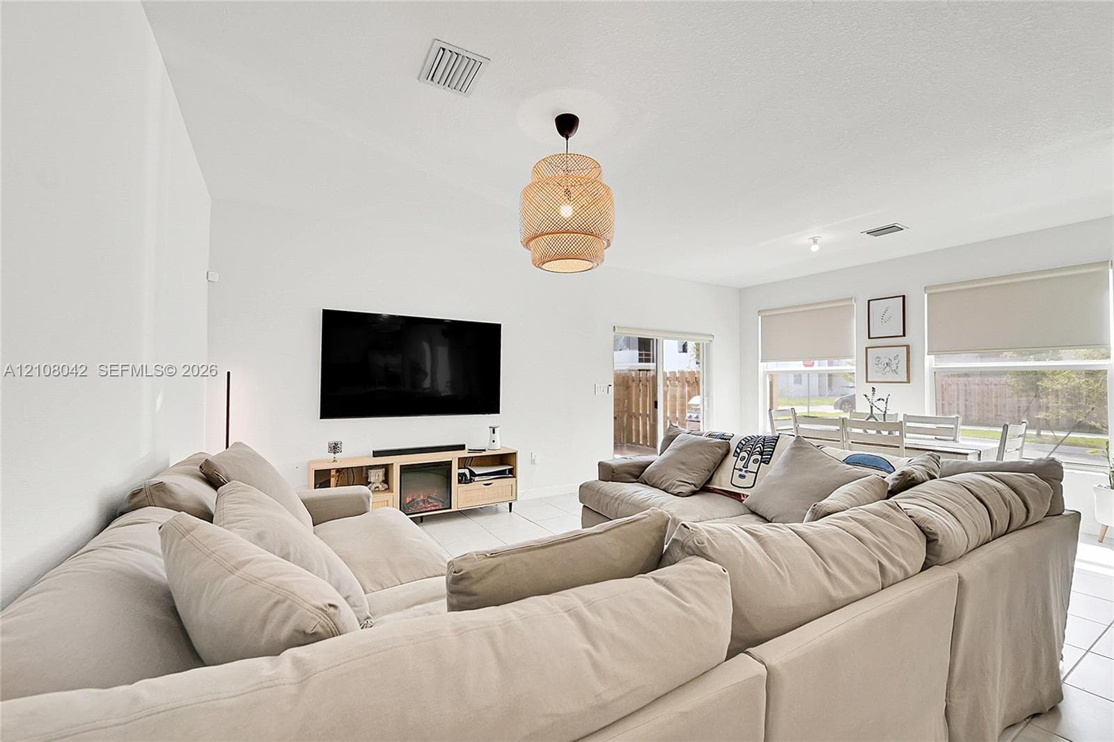 Vaulted ceilings, large-format tile flooring, textured woven pendant lighting, and oversized windows with integrated roller shades